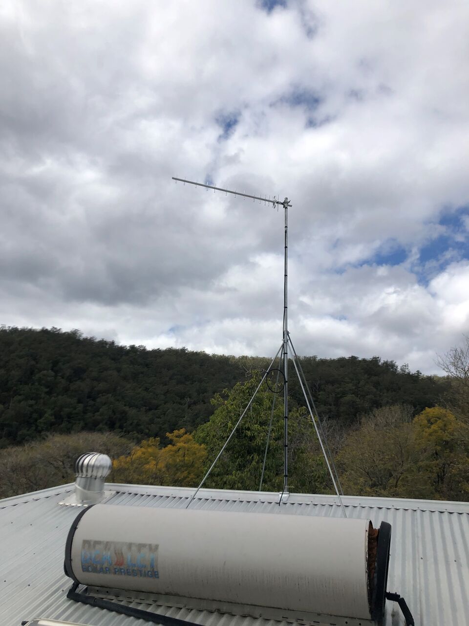 A mobile signal booster antenna mast mounted on a rural Coffs hinterland rooftop