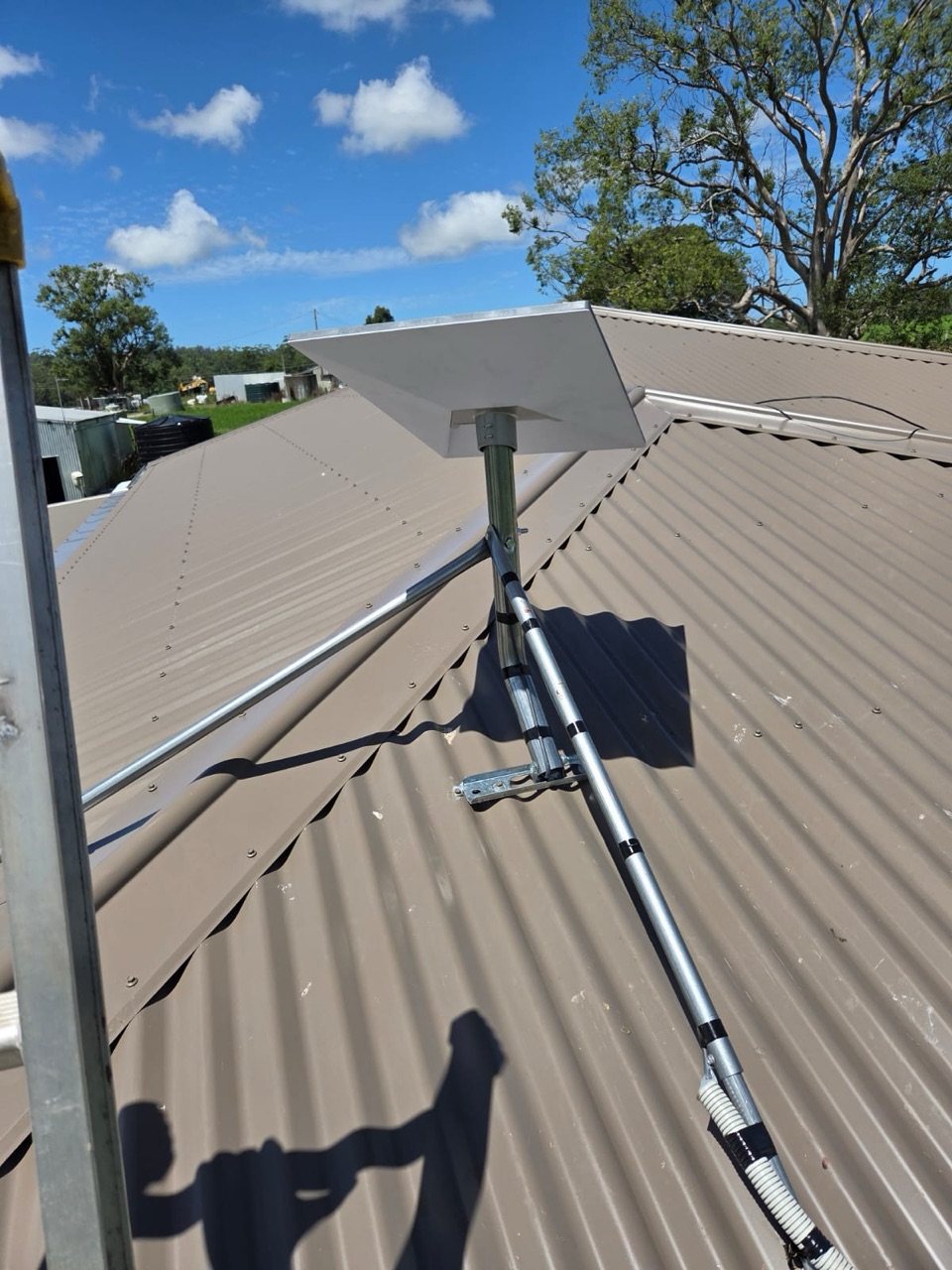 Starlink dish mounted high on a roof against a clear Coffs Coast sky