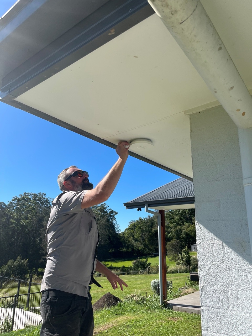 Nic from Orara TV Solutions installing a WiFi access point under the eaves of a rural home